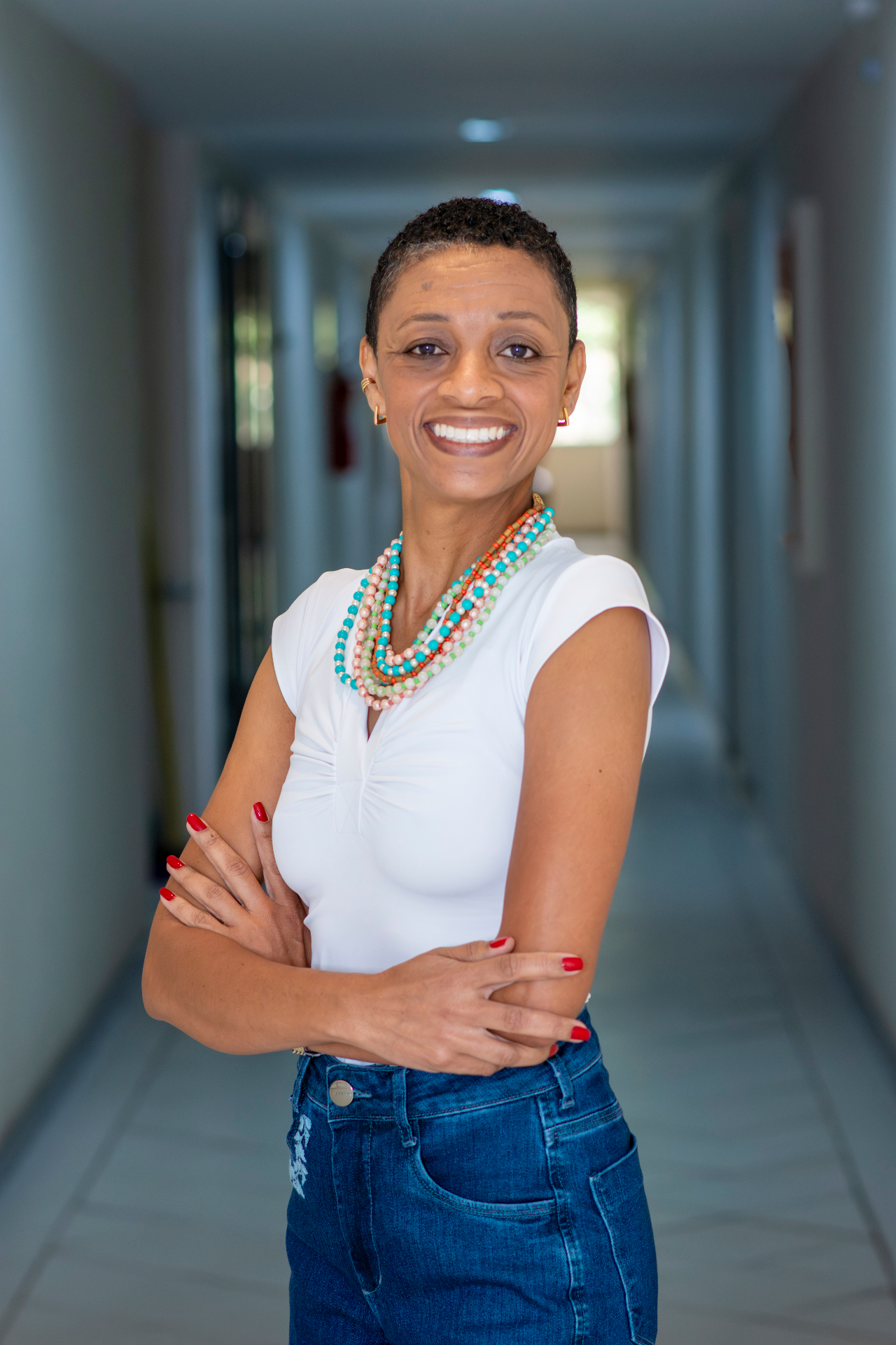 Gilmara Tomaz, psicanalista, sorrindo de braços cruzados